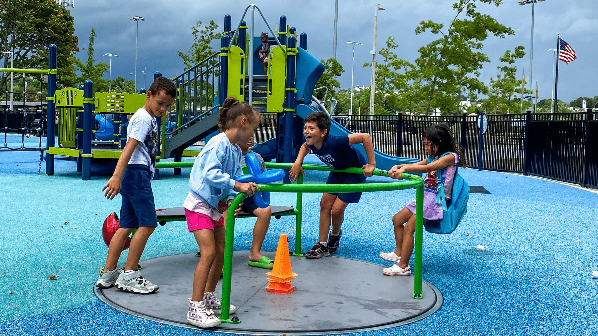 Children laughing together on a merry-go-round at a bright neighborhood playground