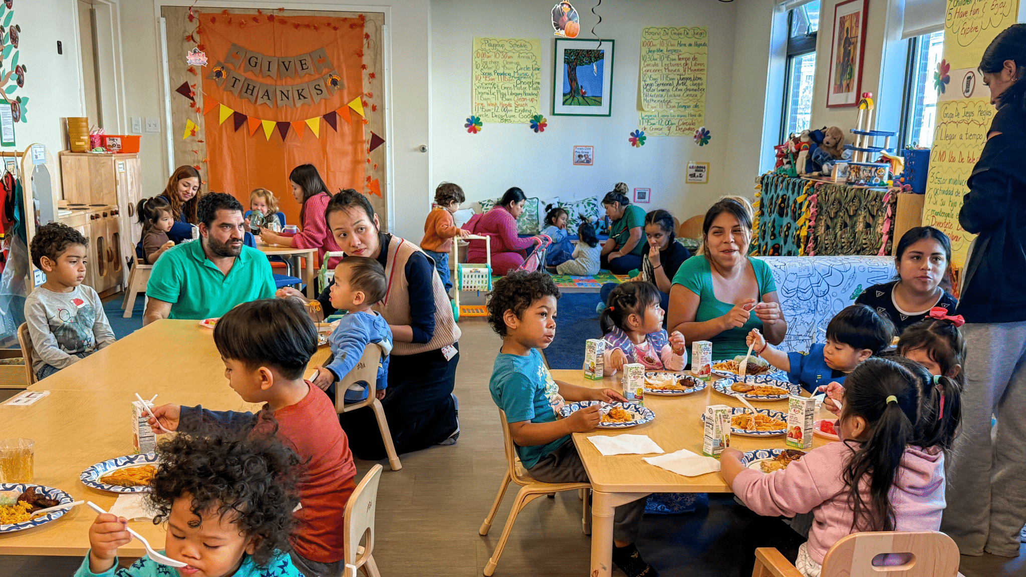 Parents and young children sharing a meal at low tables during a Family Nurturing Center playgroup