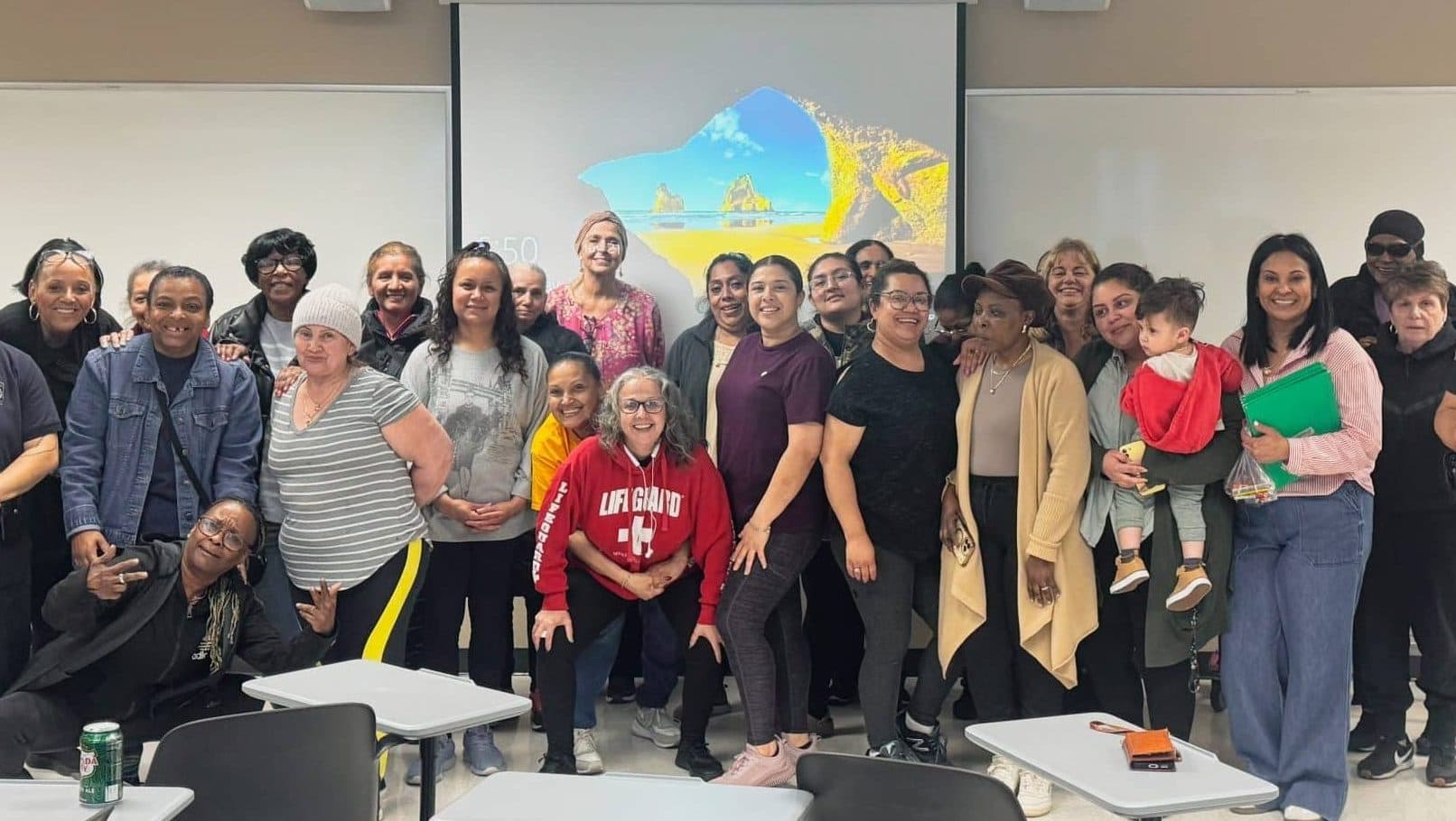 A large group of caregivers and community members smiling together for a group photo at an FNC Chelsea workshop