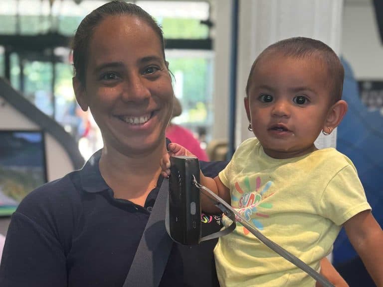 An FNC Chelsea staff member smiles while holding a baby during a family program