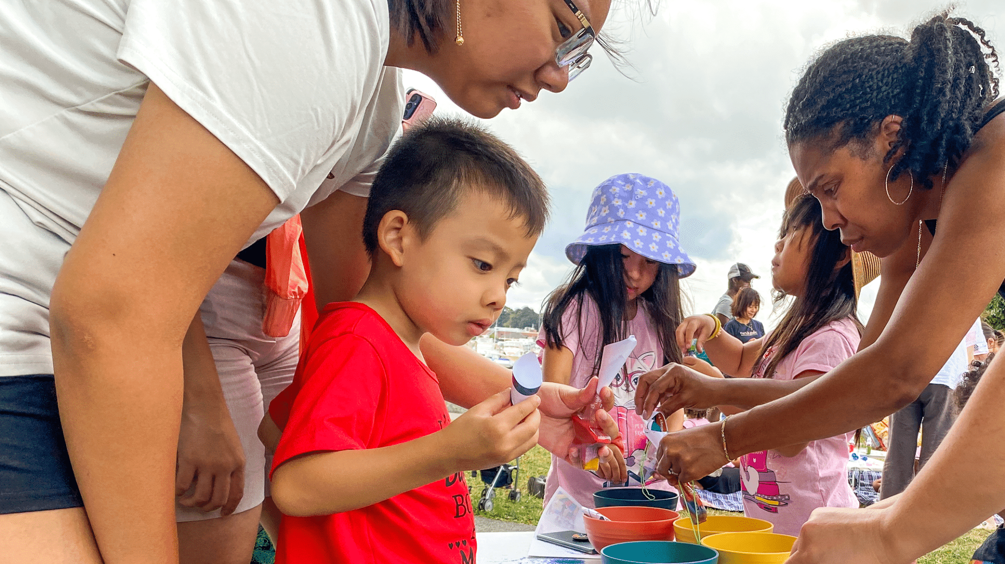 Parents and children gathered around a craft table at an outdoor FNC community event