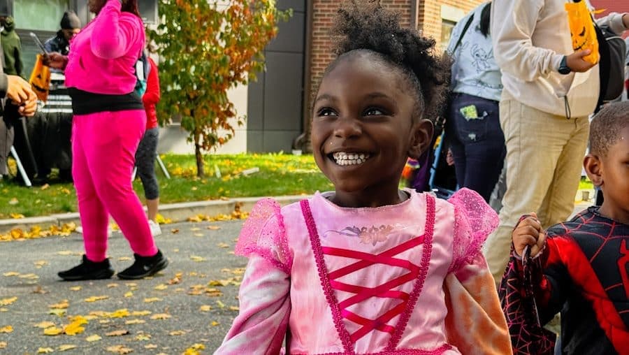 A young girl beams in a pink princess costume at an FNC fall celebration