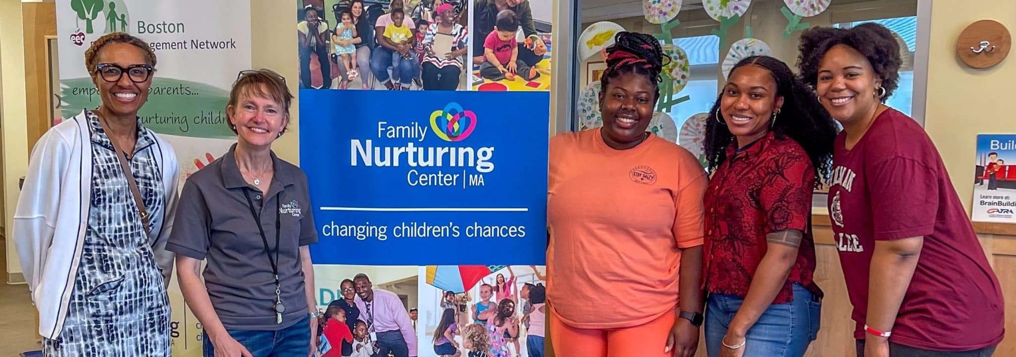 Volunteers and staff smile beside a Family Nurturing Center banner at a community baby shower.