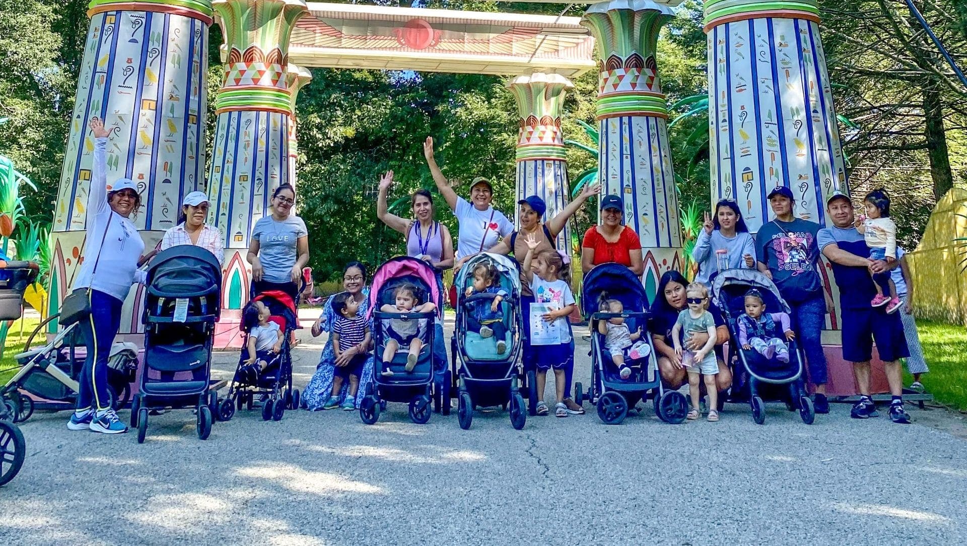 Parents and children with strollers gather under colorful painted columns at FNC Day at the Zoo.
