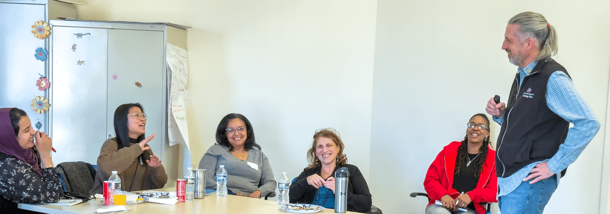 An FNC trainer leads a lively workshop discussion with providers seated around a conference table.