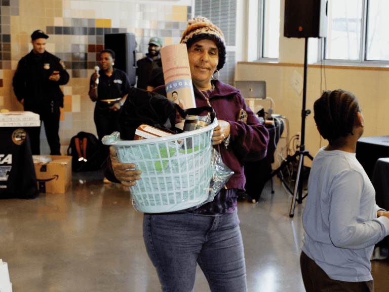 A smiling community member carries a laundry basket of raffle prizes at a family event