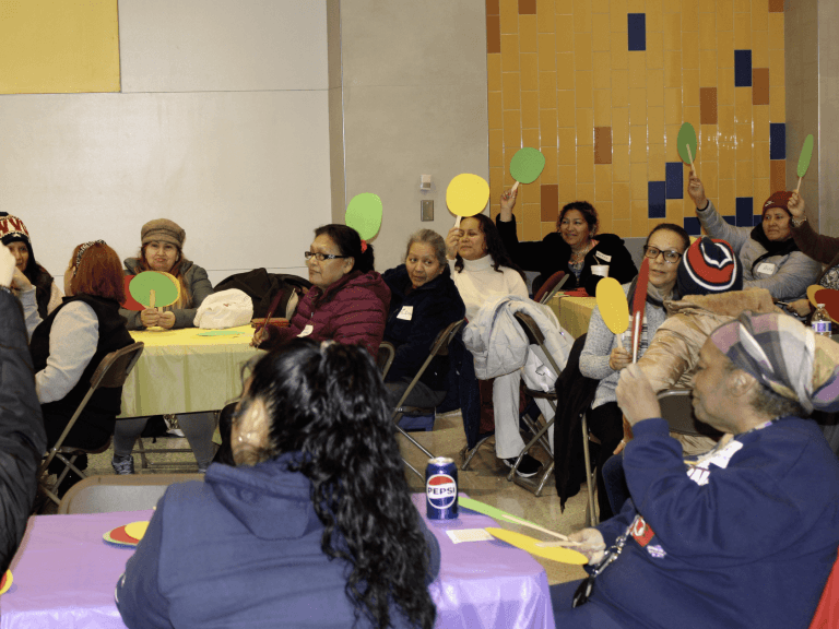 Caregivers raise colorful paddles during a group activity at a community event