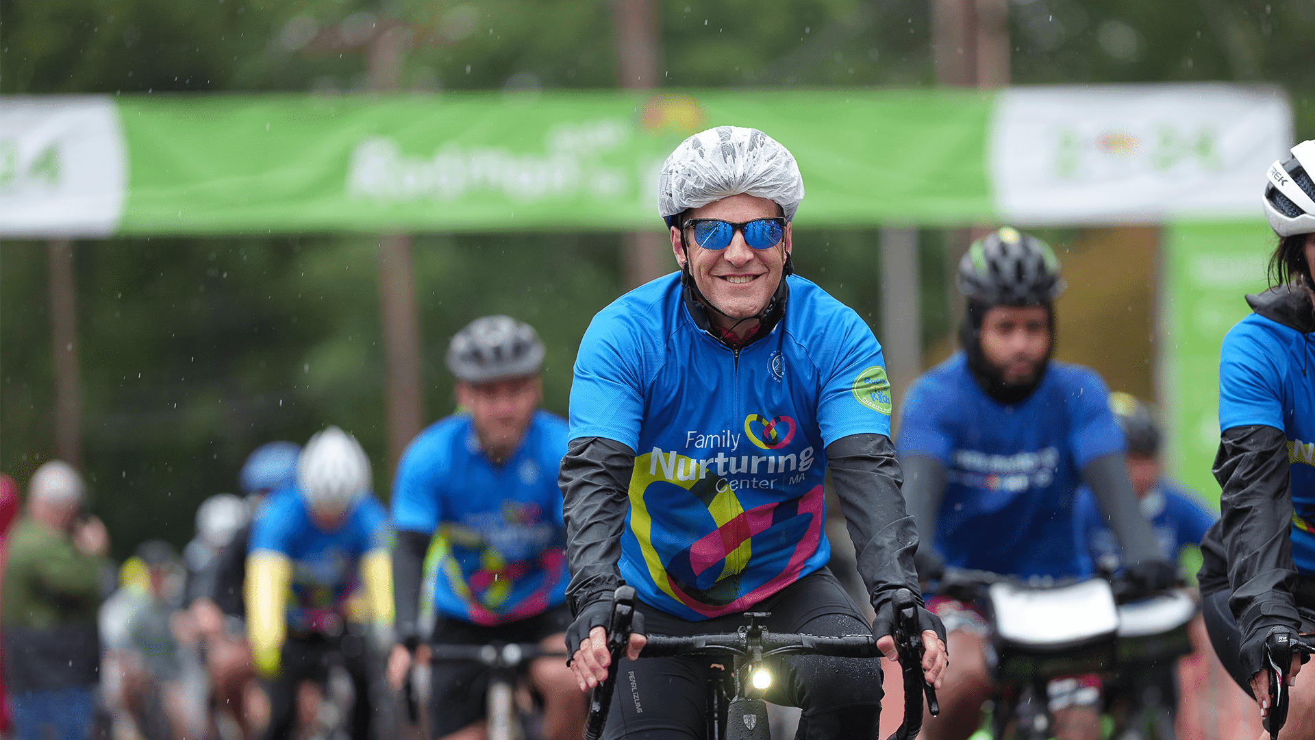 Team FNC riders in blue Family Nurturing Center jerseys pedal through the rain at the Rodman Ride for Kids